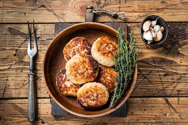 Roasted fish cutlets or patty in a wooden  plate. wooden background. Top view.