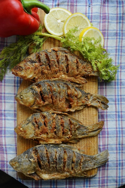 Roasted fish on cutting board with vegetables at table