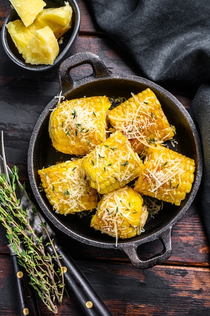 Photo roasted or grilled sweet corn cobs with garlic and butter. dark wooden background. top view.