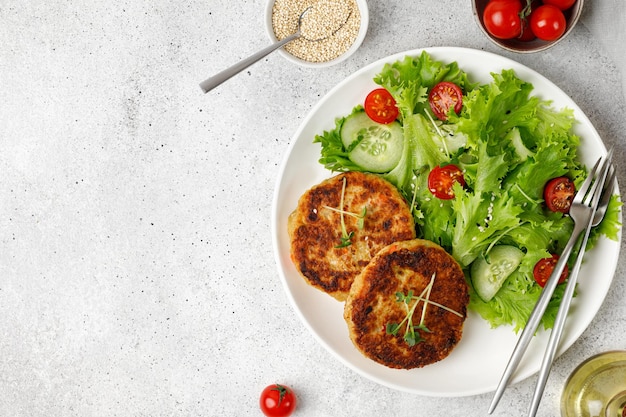 Roasted Homemade Quinoa cutlets with vegetable salad on white plate Top view copy space Vegan food