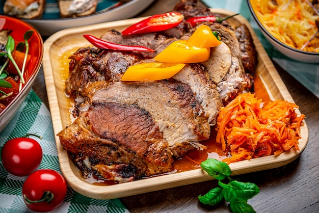 Roasted juicy pork with vegetables on a wooden plate