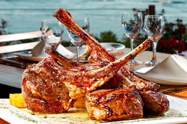 Roasted lamb chop, delicious lamb ribs roasted on the grill, with the dining table by the sea in the background