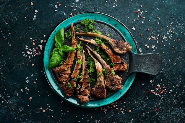 Roasted lamb chops on a dark creative restaurant background. Free copy space.