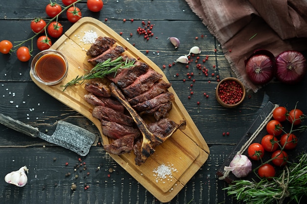 Roasted meat on a bone and fresh vegetables on a wooden cutting Board in rustic style