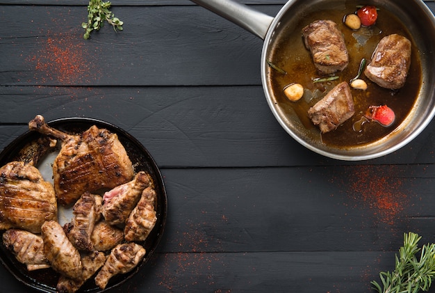 Жареное мясо на сковороде на черном деревянном фоне