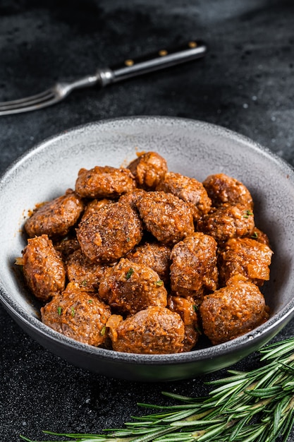 Roasted Meatballs in tomato sauce from ground beef and pork meat with rosemary. Black background. Top view.