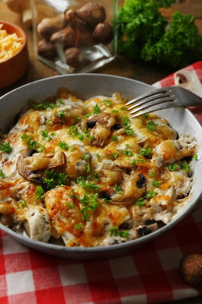 Roasted mushrooms chicken and cheese gratin in pan on wooden background