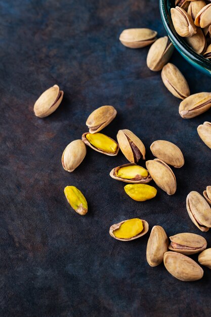 Roasted pistachios nuts on dark background. Pistachio - healthy vegetarian protein nutritious food. Healthy snack. Copy space. Top view