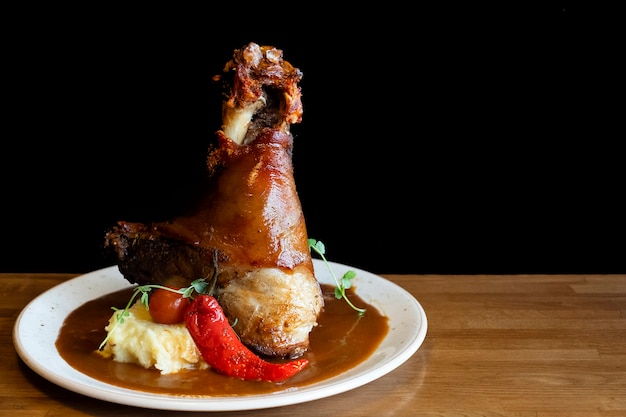 Roasted pork knuckle with mashed potatoes on a plate. Text space