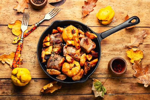 Photo roasted pork meat with autumn quince in pan