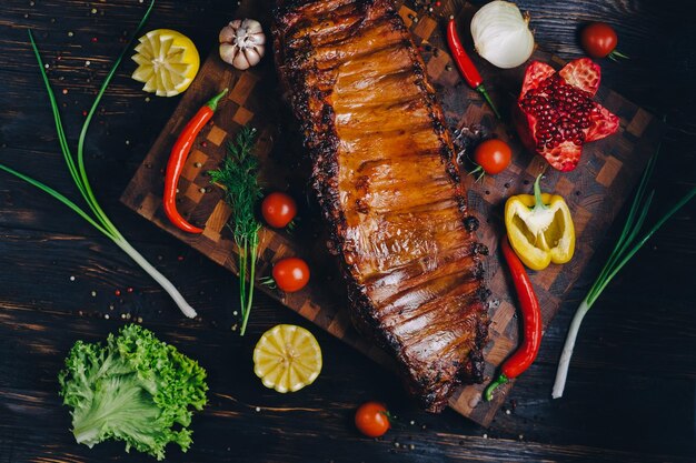 roasted pork ribs in a smokehouse standing on a cutting board garnished with rosemary pepper chili