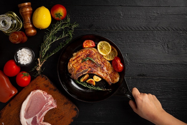 Bistecca di maiale arrosto sulla superficie di legno scuro.