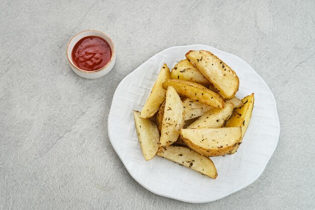 Roasted potato wedges with rosemary and herbs served with chili sauce