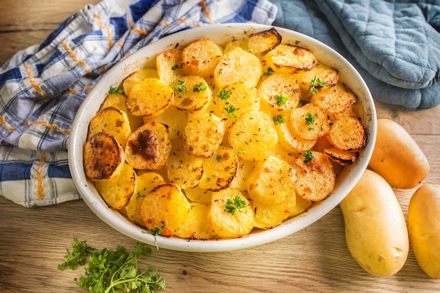 Roasted potatoes with spices and herbs on kitchen table - Top of view.