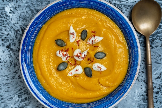 Photo roasted pumpkin and carrot soup with cream and pumpkin seeds in bowl background