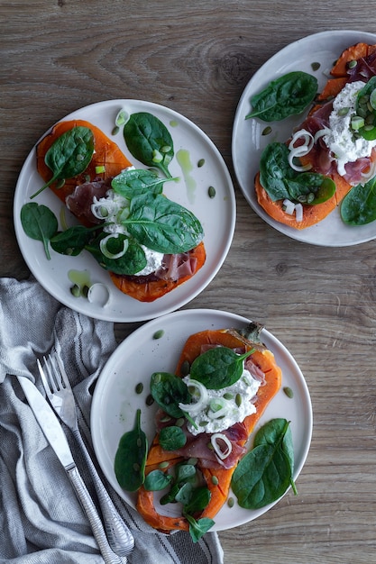 Foto zucca arrosto con ricotta, prosciutto serrano, spinaci e cipolla