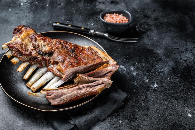 Roasted Rack of lamb ribs mutton spareribs sliced meat on plate Black background Top view Copy space