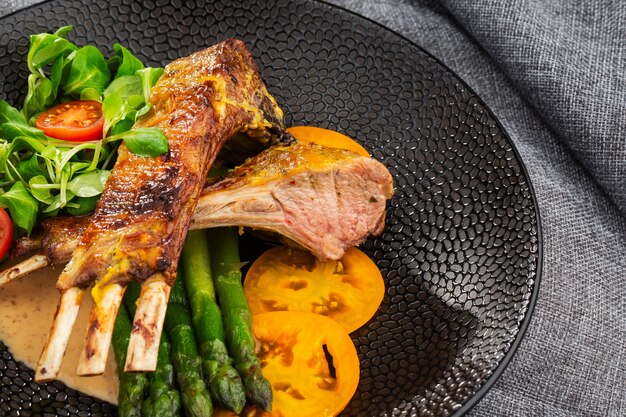 Roasted rack of lamb served with asparagus, yellow tomatoes and lamb sauce.