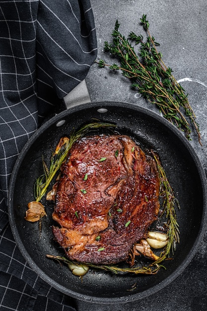 Photo roasted rib eye steak, ribeye beef meat in a pan. black background. top view.