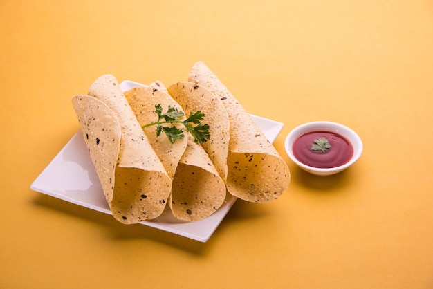 Roasted roll papad is een traditioneel Indiaas gerecht of bijgerecht, geserveerd met tomatenketchup op een kleurrijk of houten tafelblad. Selectieve focus