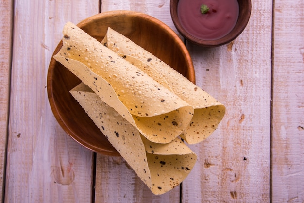 Roasted roll papad is een traditioneel Indiaas gerecht of bijgerecht, geserveerd met tomatenketchup op een kleurrijk of houten tafelblad. Selectieve focus