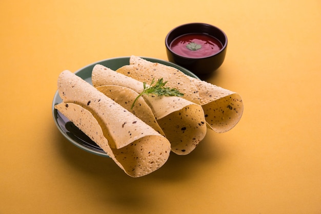 구운 롤 파파드(Roasted roll papad)는 다채로운 색상 또는 나무 테이블 위에 토마토 케첩과 함께 제공되는 인도 전통 음식 또는 반찬입니다. 선택적 초점