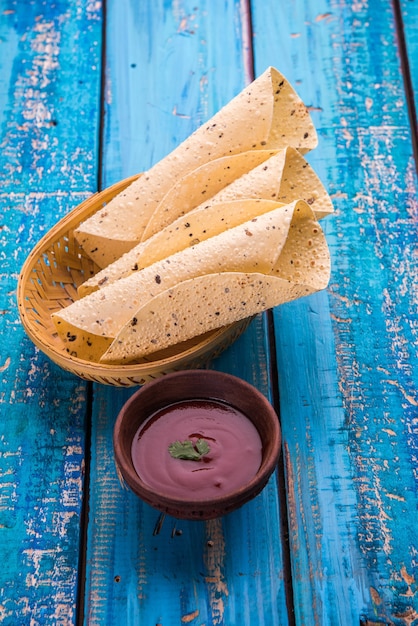 구운 롤 파파드(Roasted roll papad)는 다채로운 색상 또는 나무 테이블 위에 토마토 케첩과 함께 제공되는 인도 전통 음식 또는 반찬입니다. 선택적 초점
