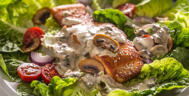 Roasted salmon fillet with fresh vegetable salad tomatoes mushrooms sauce and sesame.