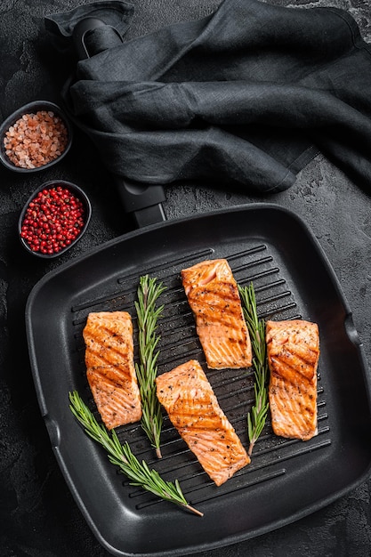 Roasted salmon fillets steaks on grill skillet black background\
top view