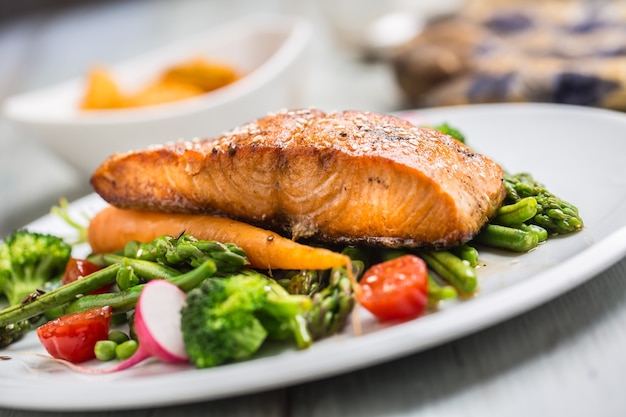 Photo roasted salmon steak with asparagos broccoli carrot tomatoes radish green beans and peas