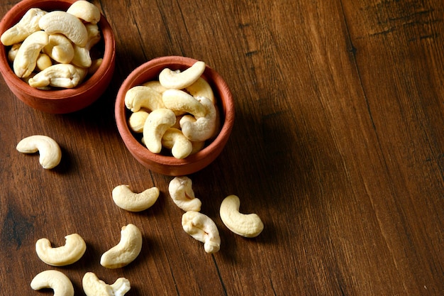 Roasted salted raw cashew nuts in a wooden bowl on rustic table, healthy vegetarian snack.