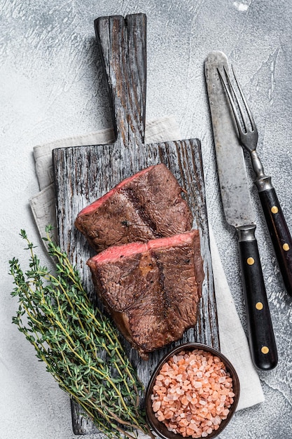 Photo roasted shoulder top blade or flat iron beef meat steaks on wooden board. white background. top view.