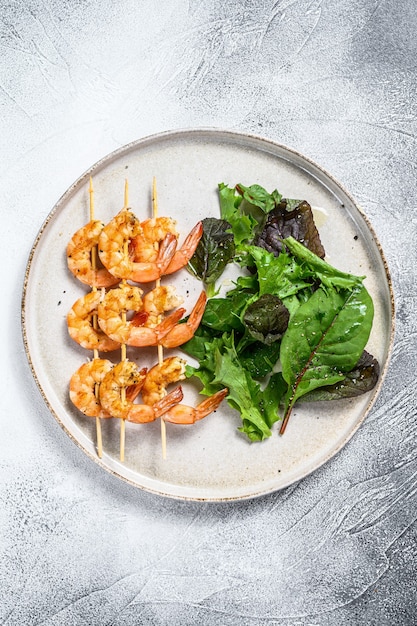 Roasted shrimps, prawns on skewers with spinach salad