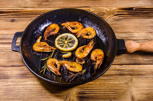 Roasted shrimps with lemon slice garlic and rosemary in a cast iron pan