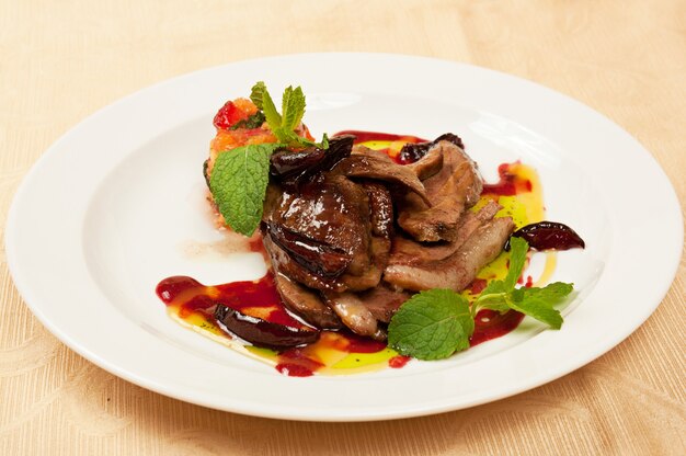 Roasted sliced goose with mint on dish in restaurant