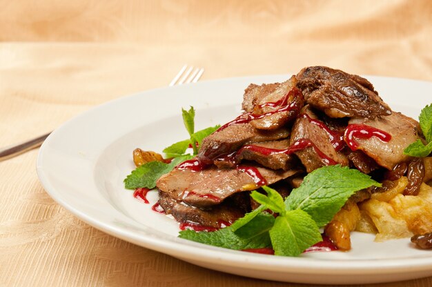 Roasted sliced goose with mint on dish in restaurant