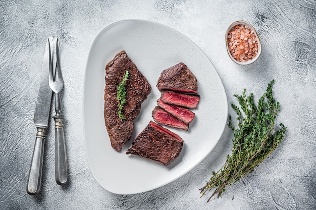 Roasted sliced rump beef meat steak on a plate with thyme