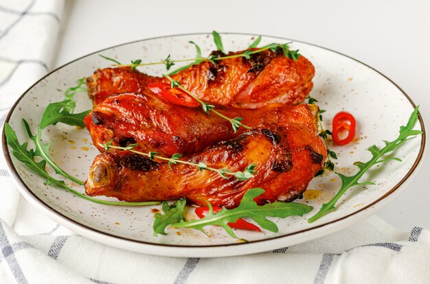 Roasted spicy chicken legs or drumsticks on a white dish. Delicious dinner or lunch concept.