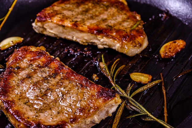 Roasted steaks with garlic, rosemary and spices in a cast iron grill pan