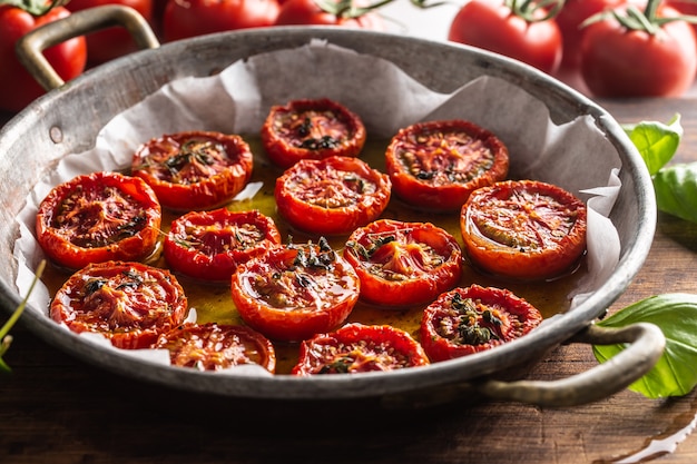 Photo roasted tomatoes with olive oil thyme oregano and basil in pan.
