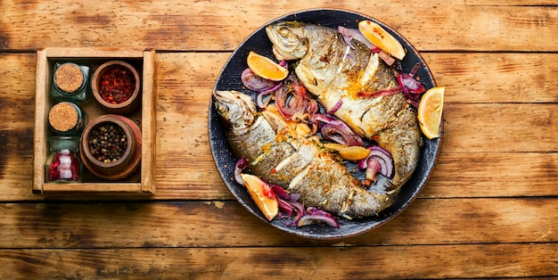 Roasted trout with lemon and onion on rustic wooden background