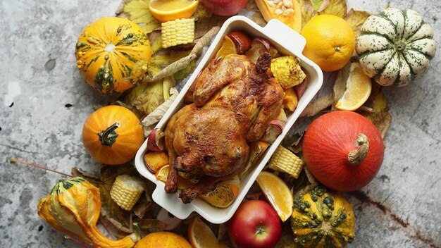 Roasted turkey or chicken with thyme served on black baking dish with potatoes pumpkins and spices on stone table thanksgiving or christmas dinner top view