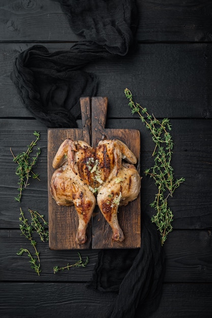 Roasted whole poussins, on black wooden table, top view