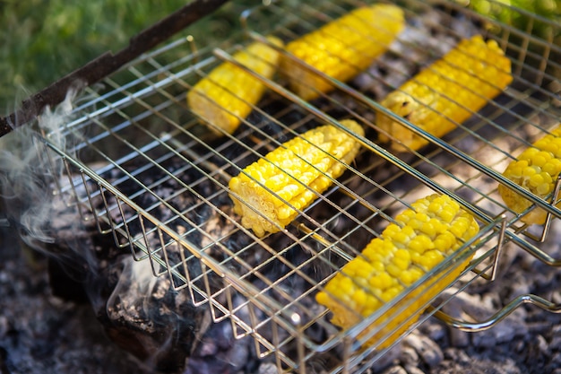 Roasted yellow juicy corn cobs, grilled on a wire rack. Weekend, outdoor recreation, sunny day.