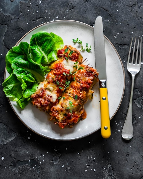 Roasted zucchini cannelloni meat filling with tomato sauce thyme and mozzarella cheese on a dark background top view