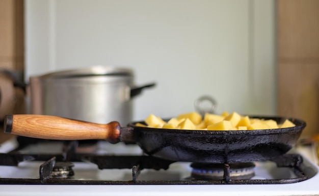 Roasting fresh potatoes in a cast iron skillet with sunflower oil A view of a stovetop with a fryi