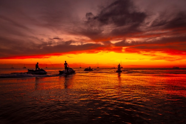 Roatan, honduras: een groep jonge mensen op een jetski bij zonsondergang op west end beach