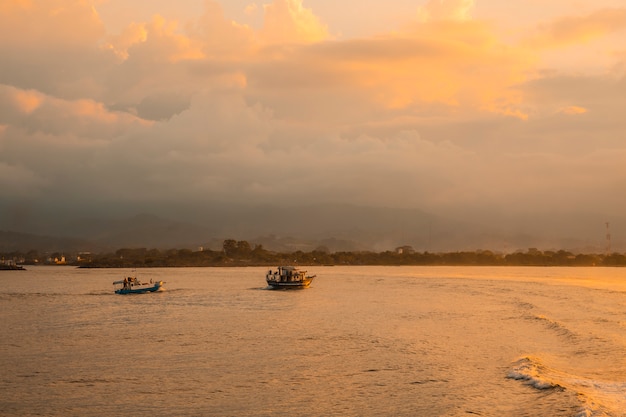 Roatan, Honduras : Fishing boats in the sea at sunset seen from the ferry heading to Roatan Island