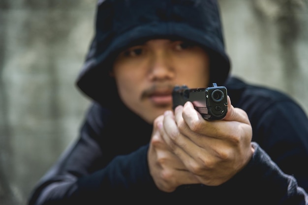 Foto crimine assassino rapinatore con cappuccio punta la pistola già spara