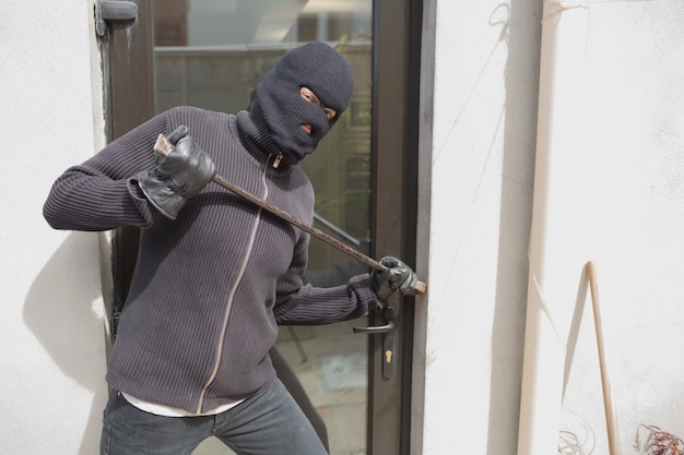 Robber breaking into house using crow bar